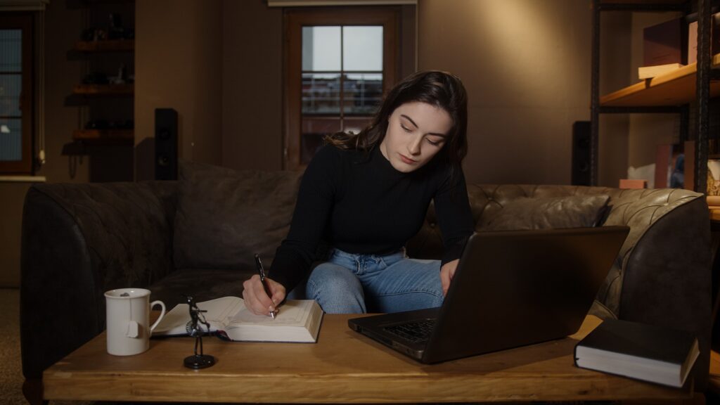 Young college or high school student pretty girl studying at table with laptop and pen paper
